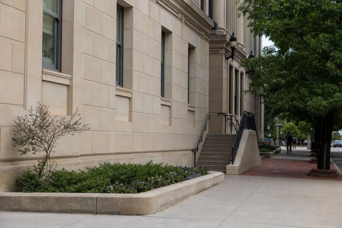 Stone courthouse exterior with steps and a tree-lined sidewalk