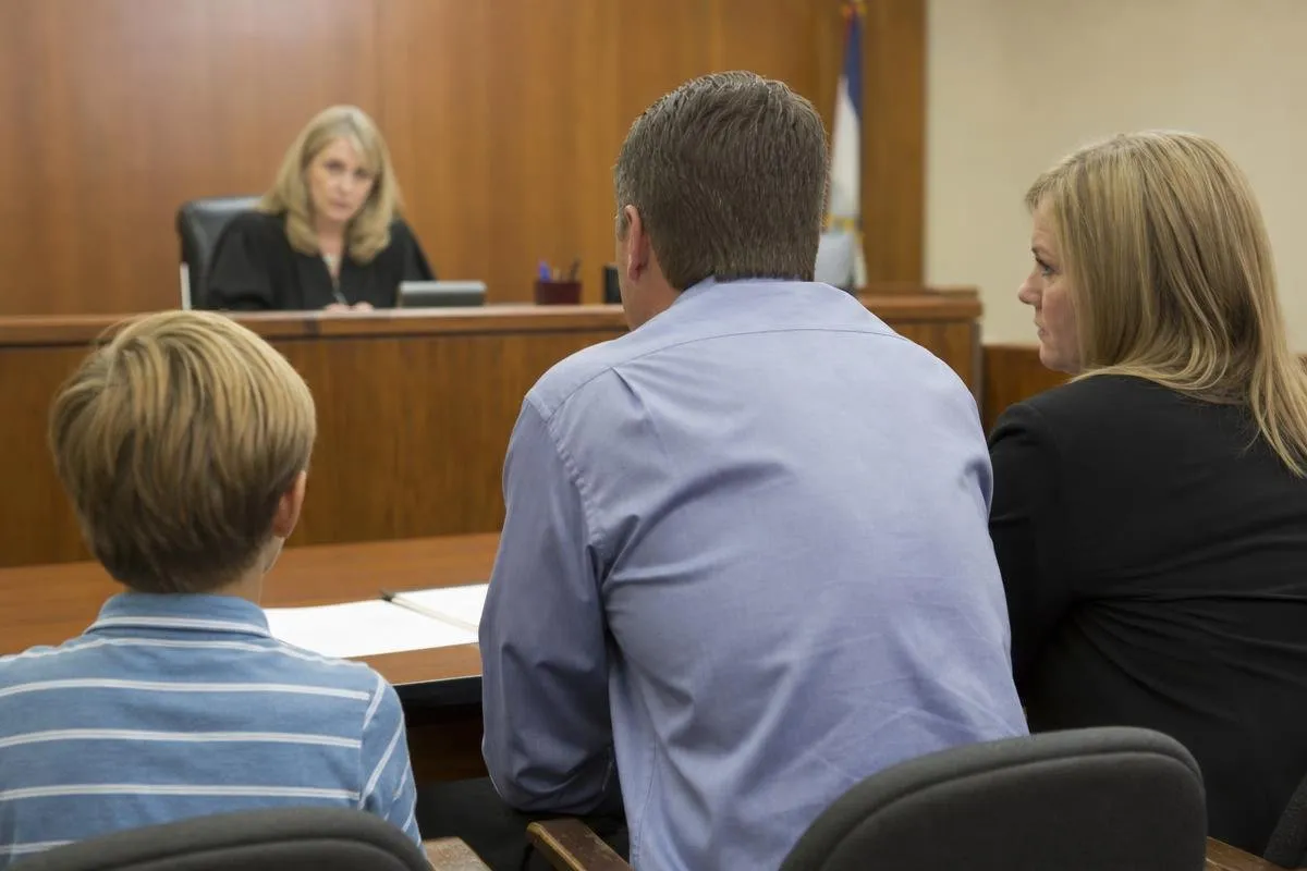 Parents and child seated before a judge during a family court hearing